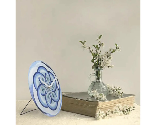 Horloge de table avec motif floral bleu sur un livre à côté d''un vase avec des fleurs