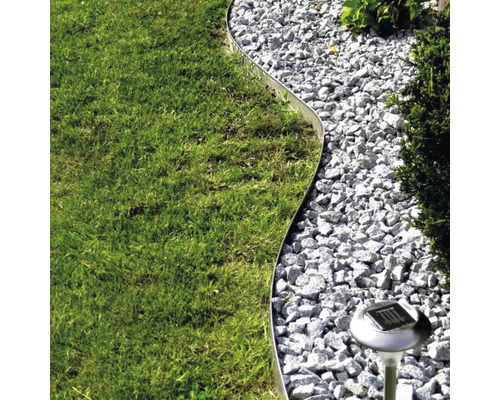 Gartenszene mit Rasen, Kiesweg, Metalleinfassung und Solarleuchte