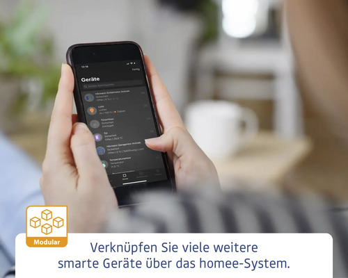 Une personne tient un smartphone avec l''application Homee pour contrôler les appareils Smart Home. Logo modulaire.