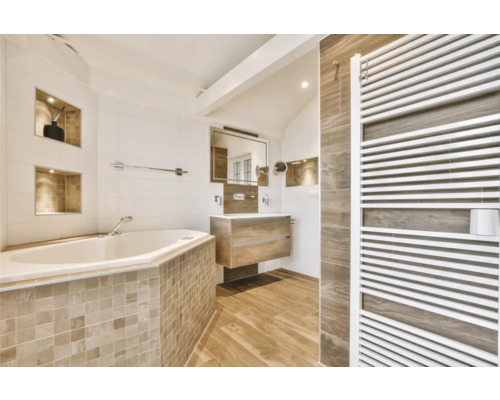 Helles Badezimmer mit Badewanne, Waschtisch, Spiegel und Heizkörper