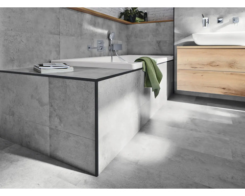 Salle de bain lumineuse avec baignoire, lavabo et carreaux gris.