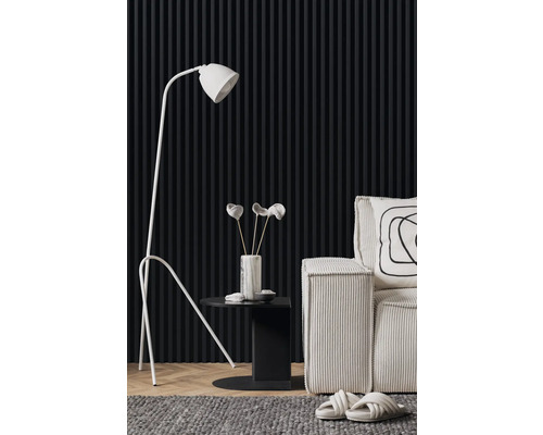 Wohnzimmerszene mit Stehlampe, Beistelltisch, Dekoration und Sessel vor einer Wand mit Paneelen