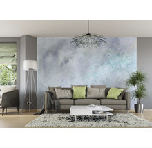 Wohnzimmer mit Sofa, Couchtisch, Stehlampe und Zimmerpflanze vor einer gemusterten Wand