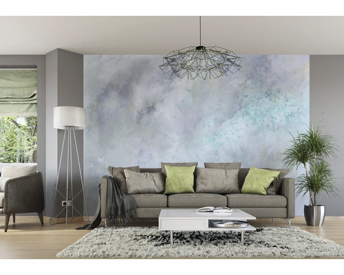 Wohnzimmer mit Sofa, Couchtisch, Stehlampe und Zimmerpflanze vor einer gemusterten Wand