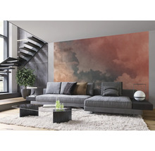 Salon avec canapé, table basse, escalier et papier peint photo nuages pour une ambiance lumineuse et moderne.