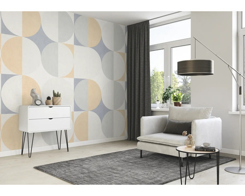 Séjour avec papier peint géométrique, fauteuil, tapis et commode