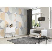 Wohnzimmer mit geometrischer Tapete, Sessel, Teppich und Kommode.