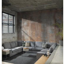 Canapé d''angle gris avec coussins et tables d''appoint dans un espace de vie industriel avec des murs en béton et une fenêtre avec des stores.