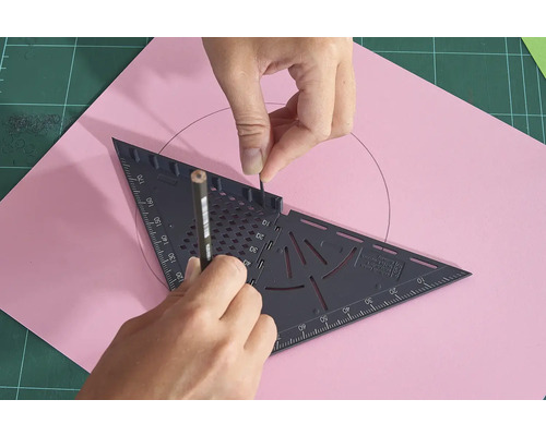 Eine Person zeichnet mit einem Bleistift und einem Dreieck einen Kreis auf ein rosafarbenes Blatt Papier.