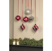 Dekorative Weihnachtsszene mit Christbaumkugeln an Bändern und Tannengirlande mit Kerzen