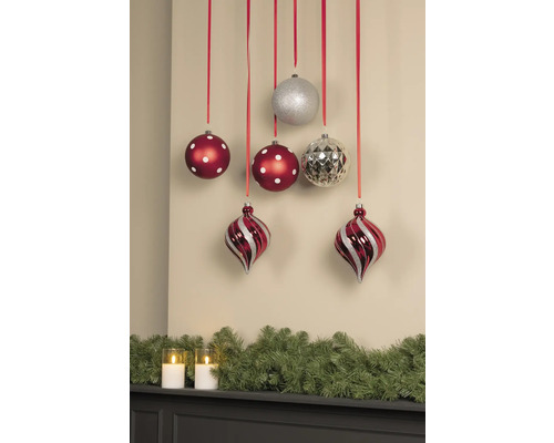 Dekorative Weihnachtsszene mit Christbaumkugeln an Bändern und Tannengirlande mit Kerzen