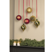 Boules de Noël décoratives suspendues à des rubans rouges au-dessus d''un manteau de cheminée avec une guirlande de sapin et des bougies