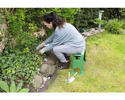 Une femme travaille dans le jardin avec un banc de jardin et des outils de jardinage.