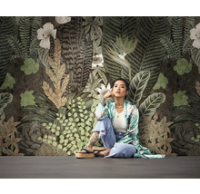 Femme assise devant un mur avec un motif de papier peint floral