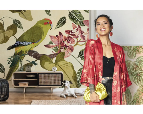 Femme en kimono rouge devant un papier peint photo floral avec des perroquets et des orchidées dans un salon lumineux