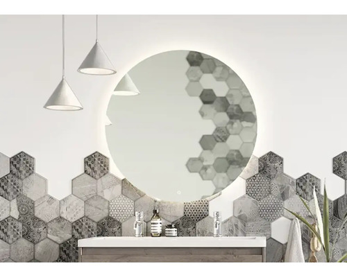Salle de bains avec miroir rond avec éclairage, lavabo et carreaux hexagonaux.
