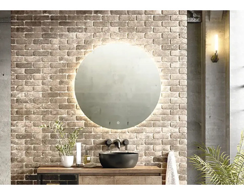 Salle de bains avec miroir rond avec éclairage, lavabo et mur en briques