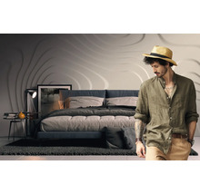 Schlafzimmer mit Bett, Nachttischlampe, Dekoration und Mann mit Hut