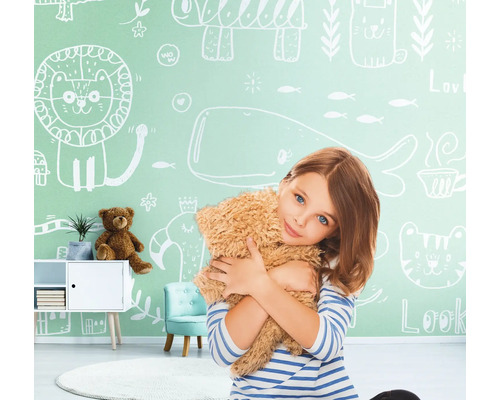 Fille étreignant un ours en peluche devant un mur avec des dessins d''animaux dans une chambre d''enfant.