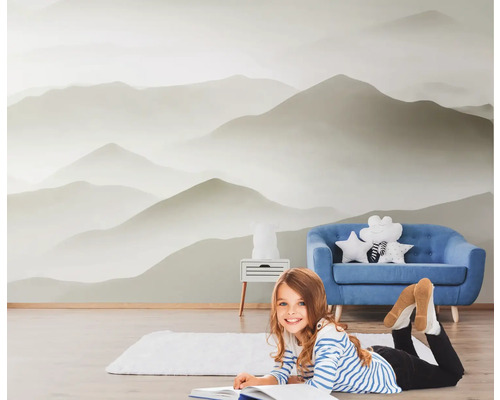 Pièce avec papier peint photo paysage de montagne, canapé bleu et enfant en train de lire