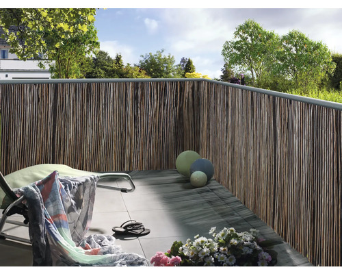 Balcon avec brise-vue en matériaux naturels, chaise longue et décoration