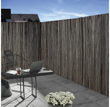 Clôture d''intimité en matériau naturel à côté d''une table de jardin avec un ordinateur portable à l''extérieur.