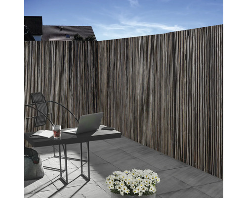 Clôture d''intimité en matériau naturel à côté d''une table de jardin avec un ordinateur portable à l''extérieur.