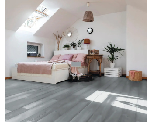 Helles Schlafzimmer im Dachgeschoss mit Bett, Tisch und grauem Holzboden