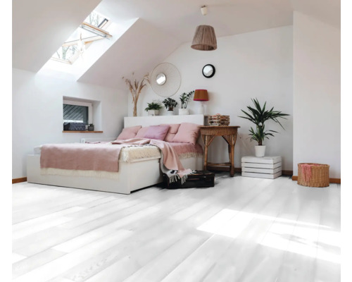Chambre lumineuse avec fenêtre de toit, lit, plancher en bois et plantes