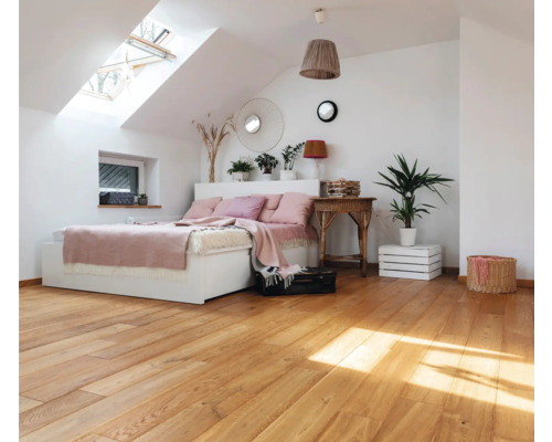 Chambre mansardée lumineuse avec parquet, lit et fenêtre de toit
