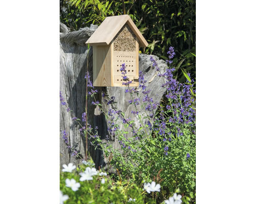 Insektenhotel aus Holz auf einem Baumstumpf im Garten