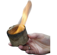 Eine Hand hält einen brennenden Anzündwürfel