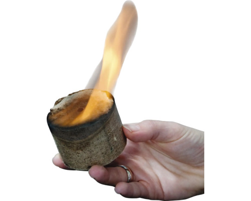 Eine Hand hält einen brennenden Anzündwürfel