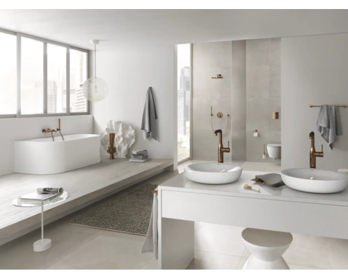 Salle de bains lumineuse avec baignoire, lavabos et robinetterie
