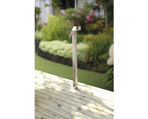 Gartenzapfstelle aus Metall auf Holzterrasse mit Garten im Hintergrund