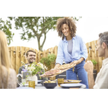 Frau serviert Pizza bei einer Gartenparty.