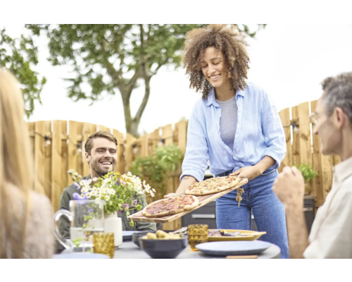 Une femme sert de la pizza dans le jardin pour une réunion conviviale