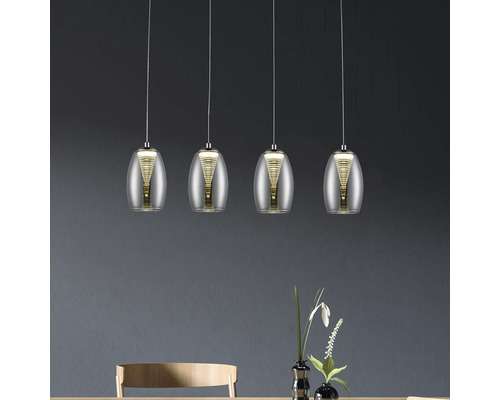 Quatre lampes avec abat-jour transparent suspendues au-dessus d''une table.