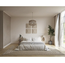 Helles Schlafzimmer mit Bett, Teppich, Lampe und Zimmerpflanze