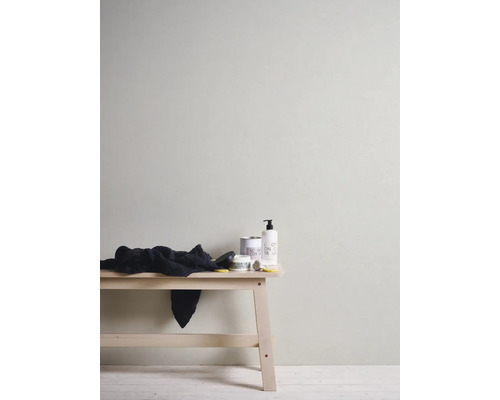 Mur avec papier peint, tabouret avec serviette et produits de soin