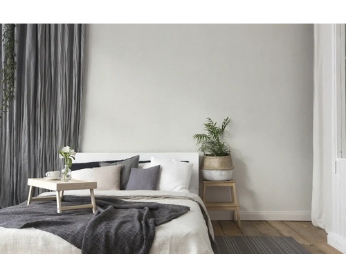 Chambre lumineuse avec lit, table de chevet, plante et rideaux