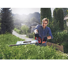 Un homme taille une haie avec un taille-haie à l''extérieur.
