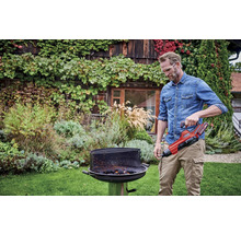 Un homme utilise un allume-barbecue dans un jardin.