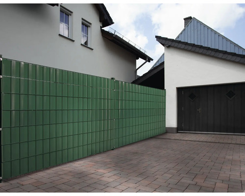 Gartenzaun aus Kunststoffelementen vor Wohnhäusern