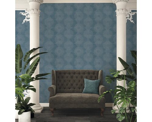 Dekoratives Interieur mit einem Sofa vor einer blauen Tapete mit Kreismuster, flankiert von Säulen und Pflanzen.
