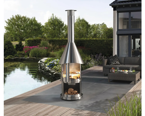 Cheminée d''extérieur en acier inoxydable avec bois et grill sur terrasse avec bassin de jardin