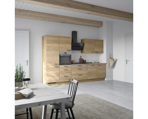 Cuisine claire avec aspect bois, hotte aspirante, four et table à manger pour une ambiance conviviale.