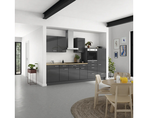 Moderne Küche mit grauen Schränken, Kochfeld, Dunstabzugshaube und Esstisch im hellen Raum.