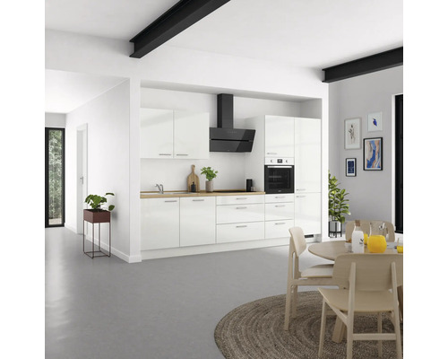 Cuisine lumineuse avec armoires blanches, hotte aspirante et plan de travail en bois dans une pièce spacieuse.