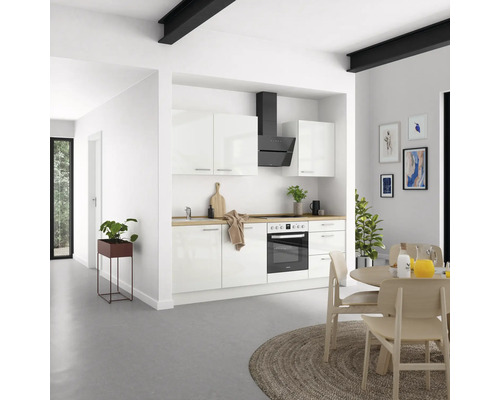 Cuisine claire avec armoires blanches, hotte aspirante et plan de travail en bois.
